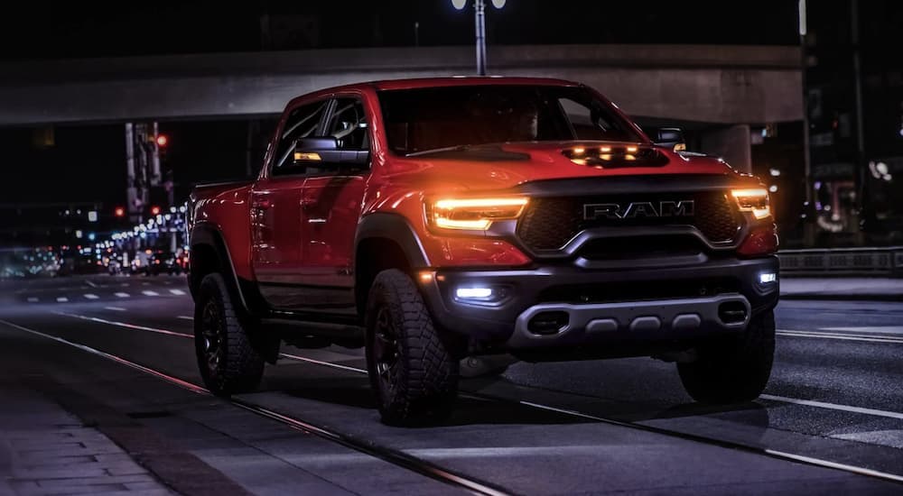 An orange 2022 Ram 1500 TRX is shown from the front driving through a city at night.