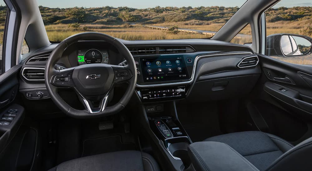 The black interior of a 2022 Chevy Bolt EV shows the steering wheel and infotainment screen.