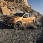 A gold 2022 Ford Ranger is shown from the front at an angle while driving off-road during a 2022 Ford Ranger vs 2022 Nissan Frontier comparison.