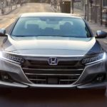 A grey 2022 Honda Accord is shown from the front while driving down a city street during a 2022 Honda Accord vs 2022 Nissan Altima comparison.