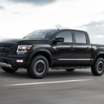 A black 2022 Nissan Titan Pro-4x is shown from the side at an angle while it drives down the highway.