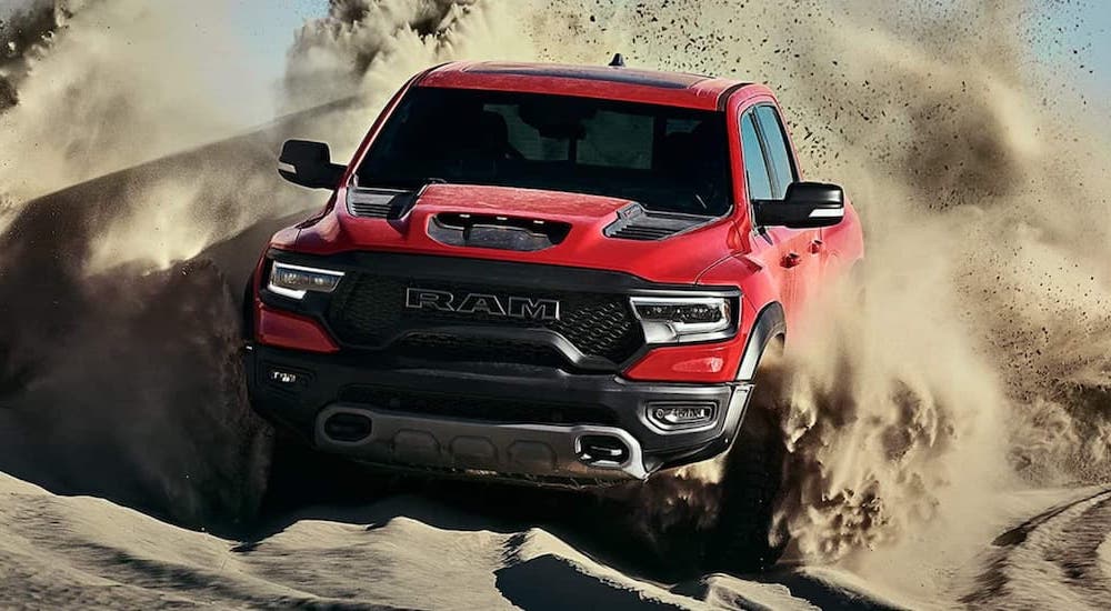 A 2021 Ram 1500 TRX is shown from the front while it drives through sand.