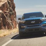 A blue 2022 Ford Explorer ST-Line is shown from the front driving past a rock face.
