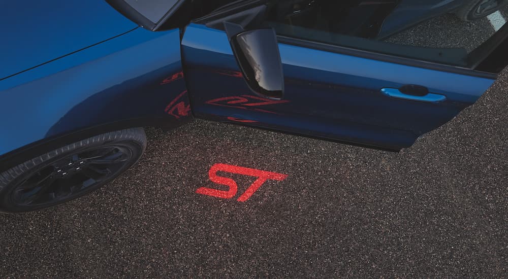 The red ST logo is shown on pavement next to a blue 2022 Ford Explorer ST-Line.