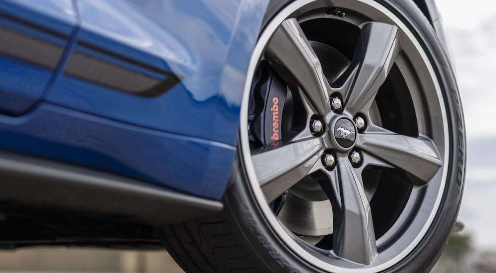 A closeup of the wheel of a blue 2022 Ford Mustang C/S is shown.