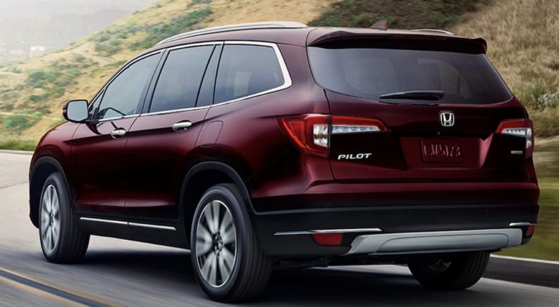 A red 2022 Honda Pilot Touring is shown from the rear driving on an open road.