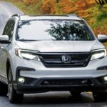 A white 2022 Honda Pilot Black Edition is shown from the front driving on an open road.