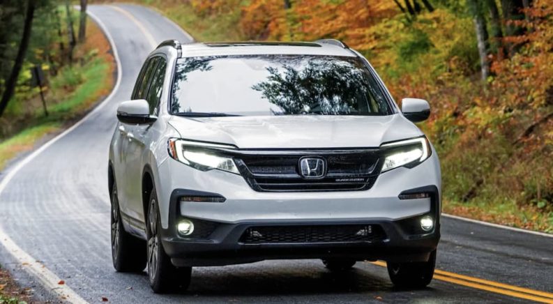 A white 2022 Honda Pilot Black Edition is shown from the front driving on an open road.