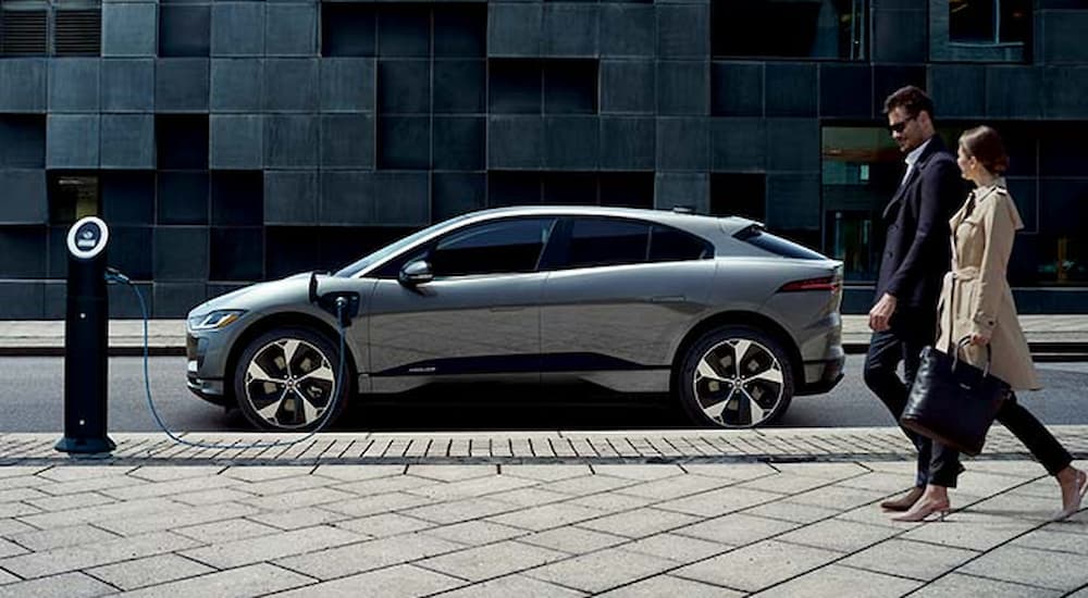 A grey 2022 Jaguar I-Pace is shown from the side while using an EV charging station.