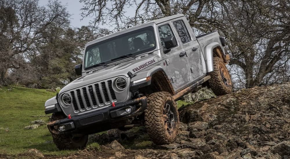 A grey 2022 Jeep Gladiator is shown from the front driving on a pile of rocks.