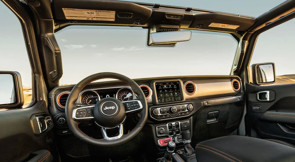 The black interior of a 2022 Jeep Gladiator shows the steering wheel and infotainment screen.
