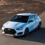 A 2022 Hyundai Veloster N is shown from the front at an angle while it rounds a bend.
