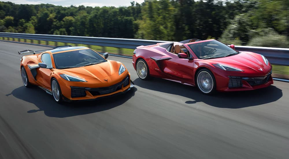 An orange and a red 2023 Chevy Corvette Z06 are shown driving next to each other on a track.