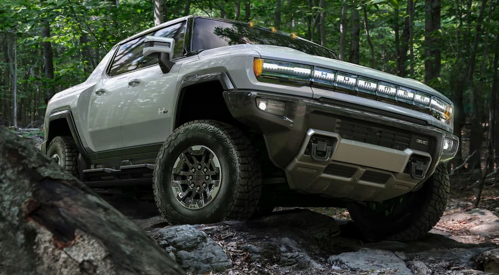 A grey 2022 GMC Hummer EV is shown from the front while it climbs over rocks after the owner searched 'GMC dealer near me'.