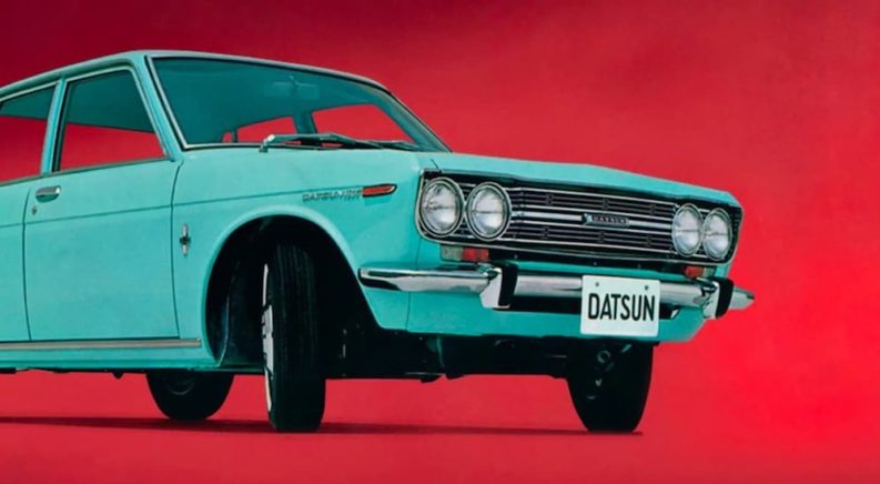 A teal 1970 Datsun 510 is shown from the front at an angle on a red background.