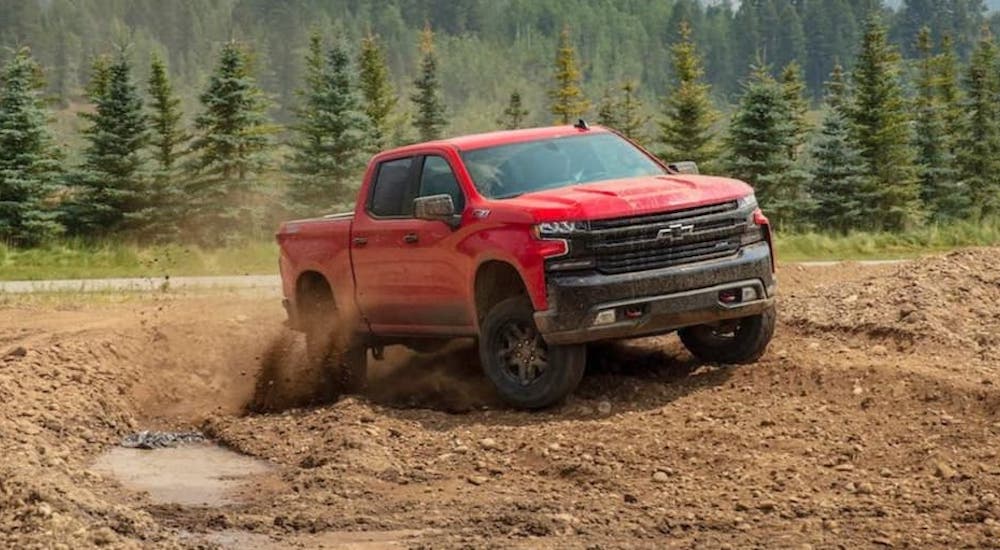 A red 2022 Chevy Silverado 1500 Z71 is shown from the front while driving through mud.
