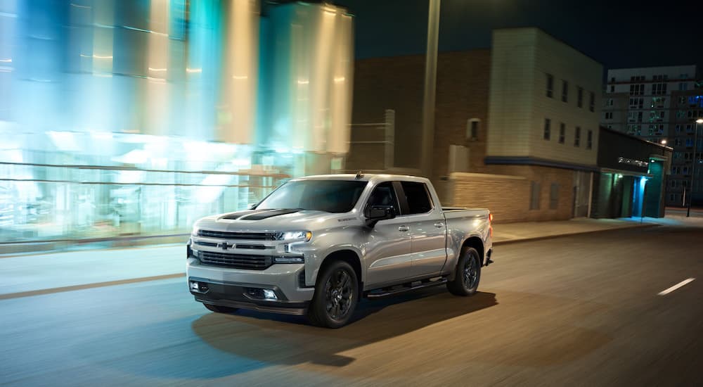 A silver 2022 Chevy Silverado 1500 is shown from the side on a city street.