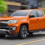 An orange 2022 Chevy Colorado Z71 is shown from the front at an an angle on a city street.