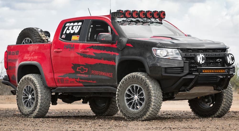A red and black 2022 Chevy Colorado ZR2 race truck is shown from the side while parked off-road.