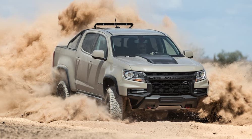 A tan 2022 Chevy Colorado ZR2 is shown from the front while sliding through sand.