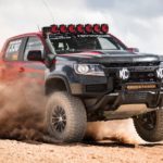 A red and black 2021 Colorado ZR2 race truck is shown jumping through sand.