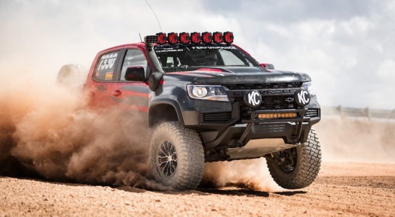 A red and black 2021 Colorado ZR2 race truck is shown jumping through sand.