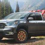 A grey 2022 Honda Ridgeline is shown from the front at an angle while loaded with a pair of dirt bikes
