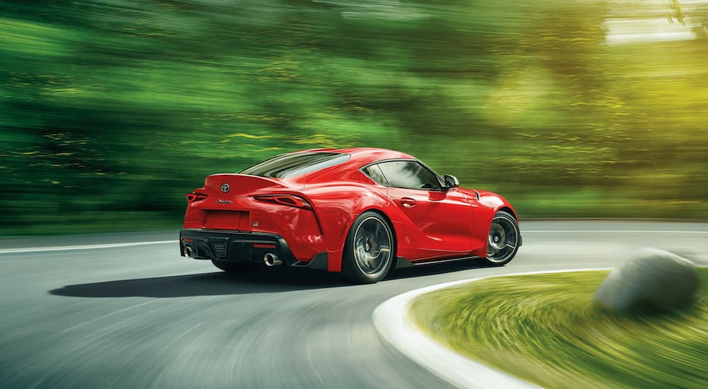 A red 2021 Toyota Supra is shown from the rear while it takes a corner.