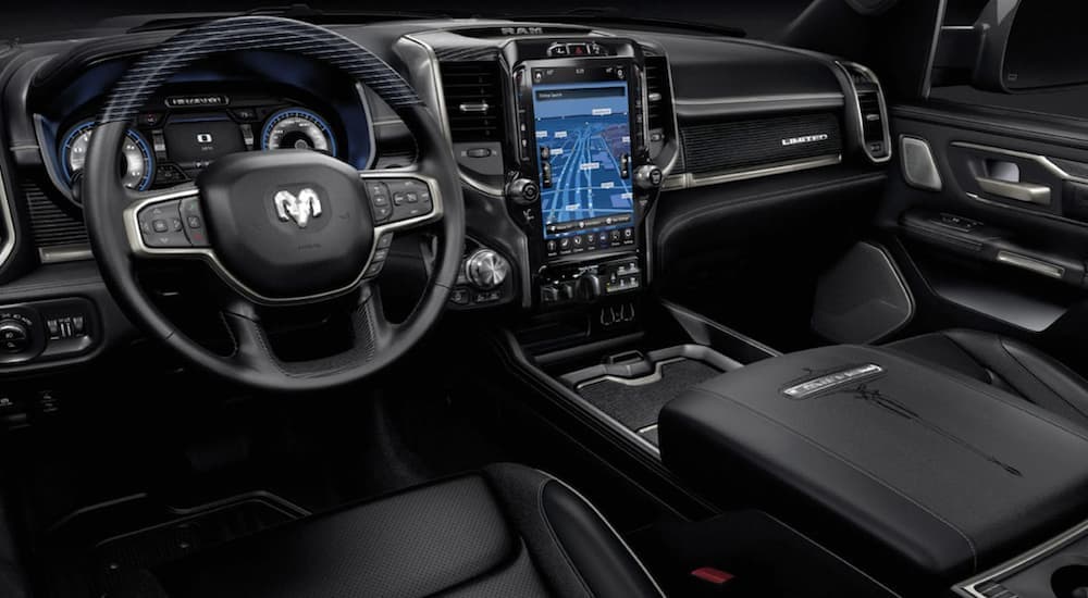 The black interior of a 2022 Ram 1500 shows the steering wheel and infotainment screen.