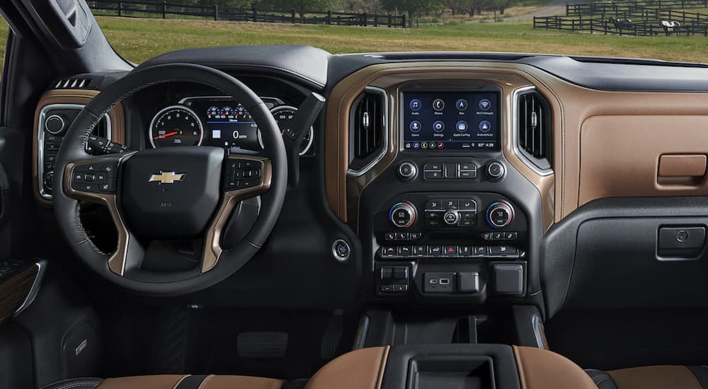 The black and brown interior of a 2022 Chevy Silverado 1500 shows the steering wheel and infotainment screen during a 2022 Chevy Silverado 1500 vs 2022 Ram 1500 comparison.