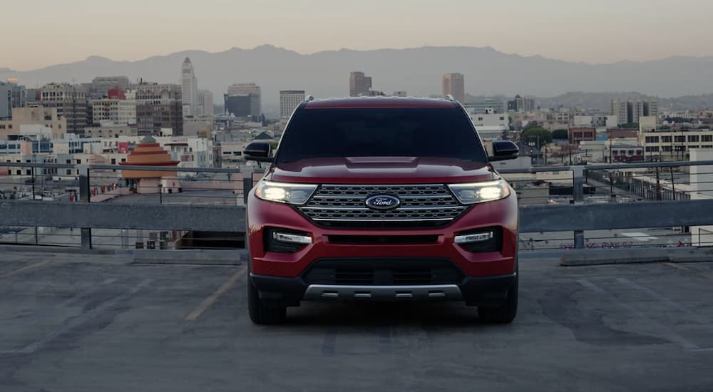 A red 2022 Ford Explorer is shown from the front parked on a rooftop overlooking a city.