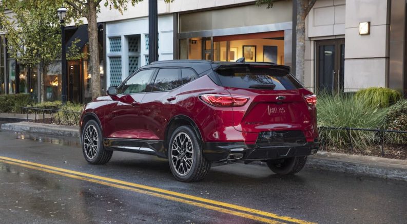 A red 2023 Chevy Blazer RS is shown from the rear while driving on a city street.