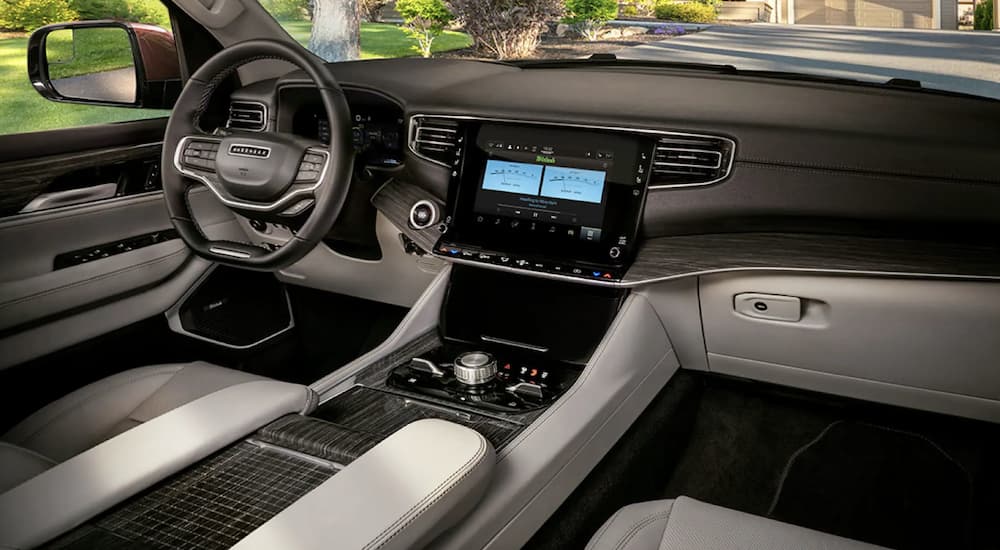 The black and white interior of a 2023 Wagoneer L shows the steering wheel and infotainment screen.