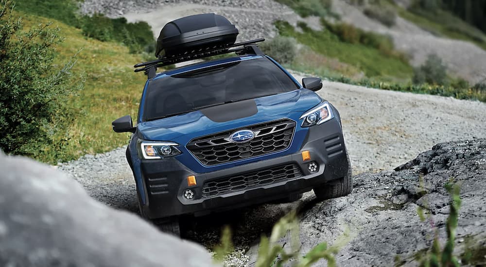 A blue 2022 Subaru Outback Wilderness is shown parked on a rock pile. 