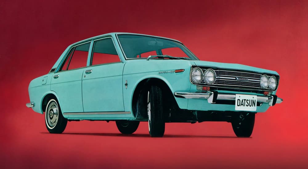 A blue 1970s Nissan Datsun is shown on a red background.