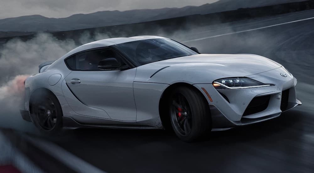 A white 2022 Toyota GR Supra is shown from the front at an angle while drifting through a corner.