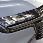 A close up shows the passenger side headlight on one of the most popular vehicle at used car dealers, a white 2021 Chevy Suburban.