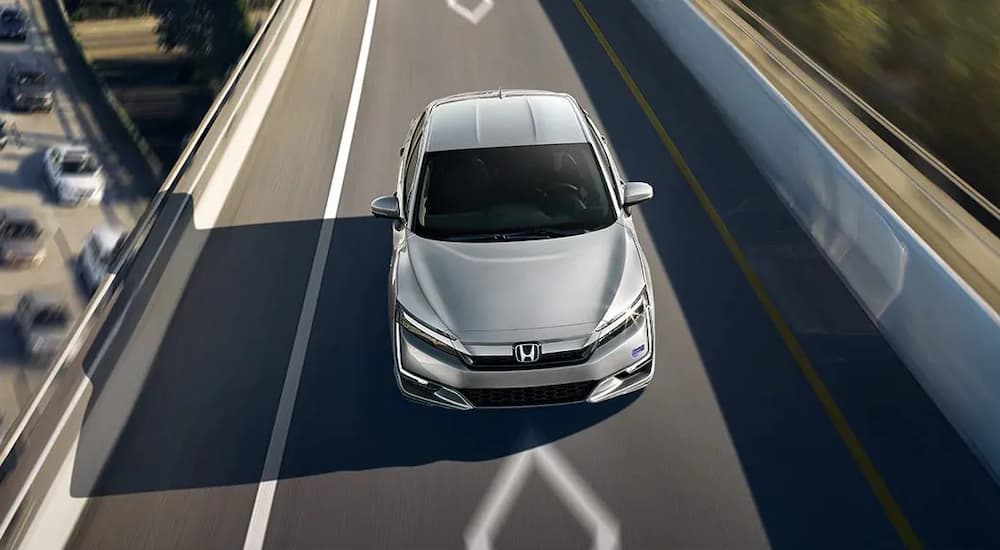 A silver 2020 Honda Clarity Plug-In Hybrid is shown driving on a bridge.