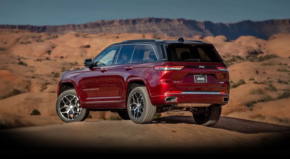 A red 2022 Jeep Grand Cherokee is shown from the rear while off-road.