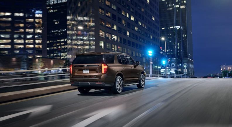 A brown 2023 Chevy Tahoe RST is shown from the rear in a city at night.