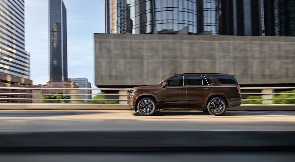 A brown 2023 Chevy Tahoe RST is shown from the side while driving on the highway.