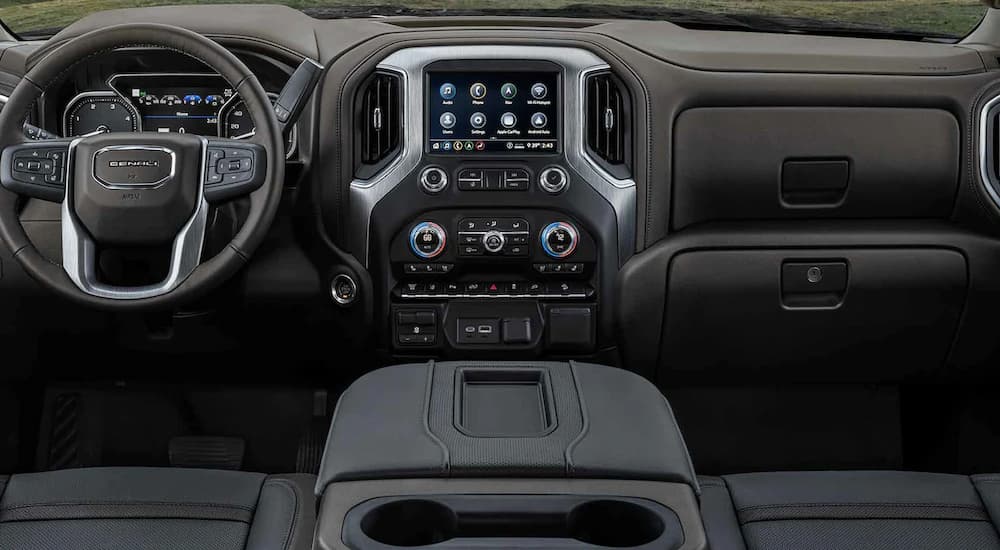 The black interior of a 2022 GMC Sierra 2500HD shows the steering wheel and center console.