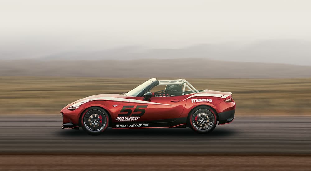 A red 2022 Mazda MX-5 Miata is shown from the side on a racetrack.