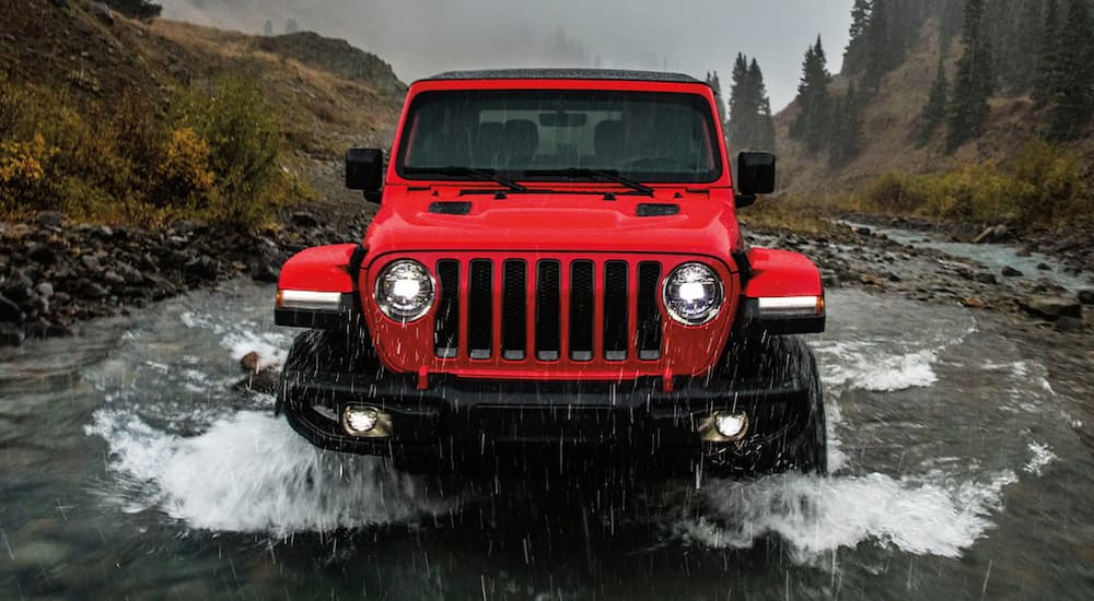 A red 2022 Jeep Wrangler Unlimited Rubicon is shown driving through a river.