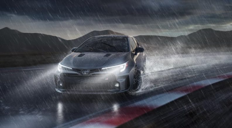 A silver 2023 Toyota GR Corolla is shown drifting in the rain.