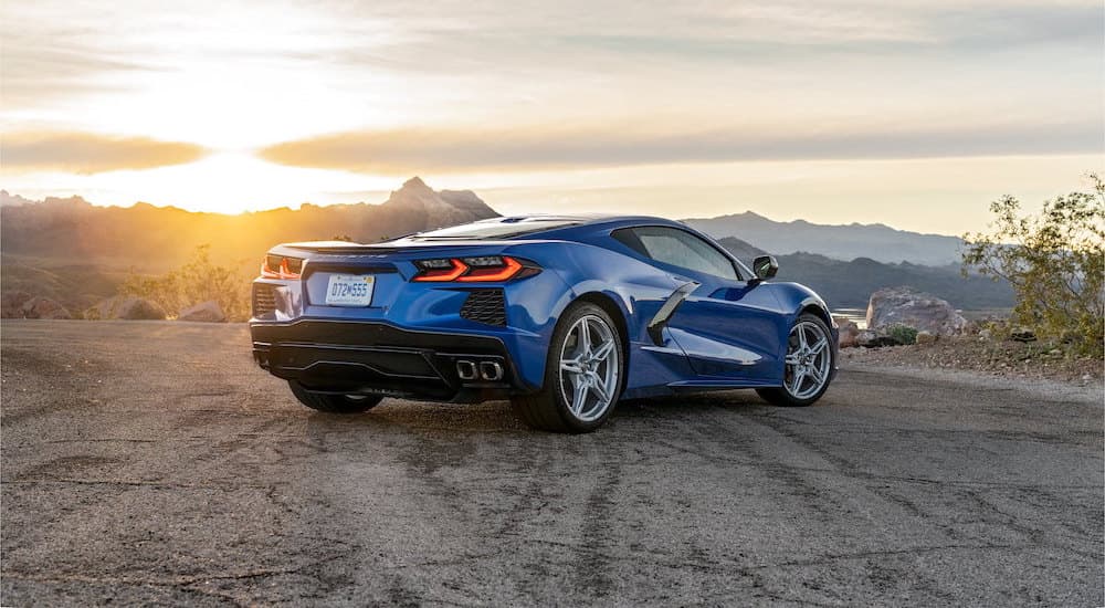 A blue 2023 Chevy Corvette is shown from the rear parked in front of mountains.