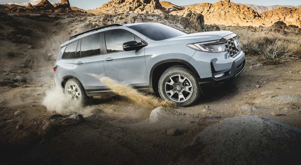 A grey 2022 Honda Passport Trailsport is shown off-roading on a dusty trail.
