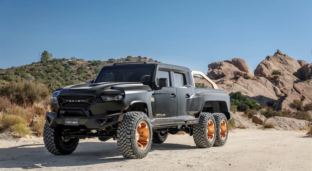 A black 2022 Rezvani Hercules 6x6 is shown driving on a desert road.