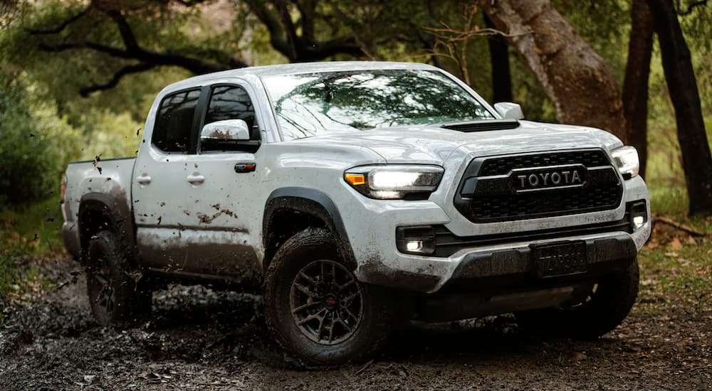 A white 2022 Toyota Tacoma TRD Pro is shown from the front while driving through the mud.