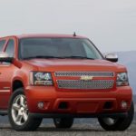 An orange 2011 Chevy Avalanche is shown parked after leaving a used truck dealer.